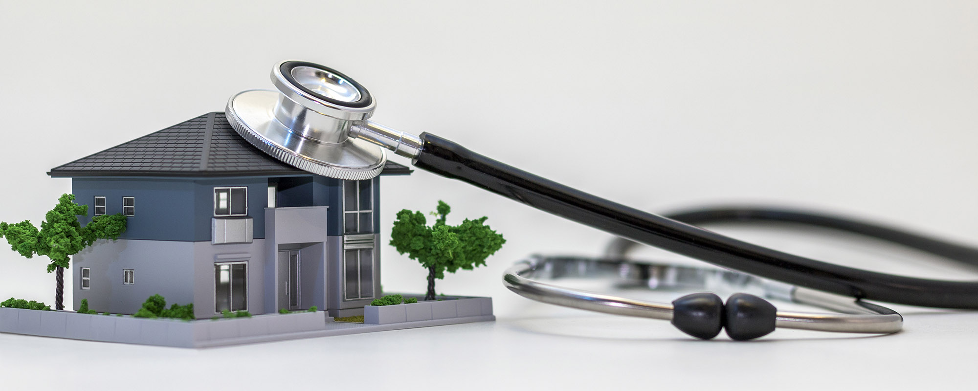 A model home being examined with a stethoscope, diagnostic mold inspection